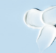 A moisturiser with urea in it is spread across a blue surface, forming four distinct white cream blobs.