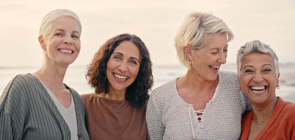 Four women smiling at the camera - going through the menopause and experiencing itchy, dry menopausal skin